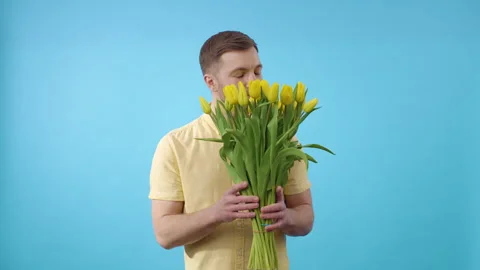 Man standing in front of blue background with yellow tulips Stock Footage 266451725