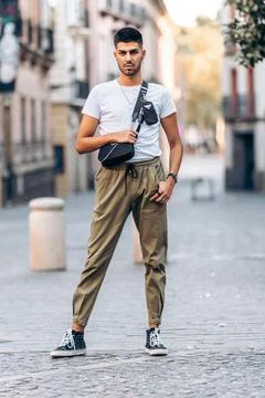 Man standing in front of the camera with casual clothes and a black handbag Stock Photos