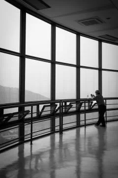 A man standing in front of large windows Stock Photos