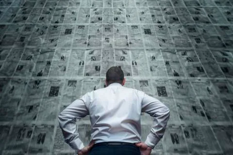 A man is standing in front of newspaper wall and reading the daily updates. D 写真素材