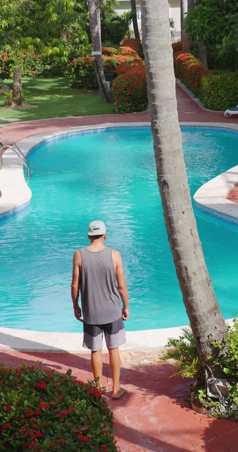 Man standing in front of poolside at hotel in tropical environment. Back view. Stock Footage 249633360