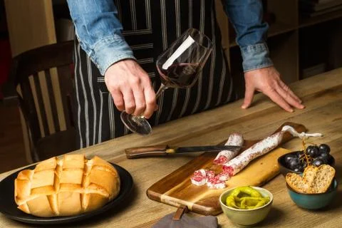 Man standing in front of a table with appetizers and a glass of wine in his hand Foto stock
