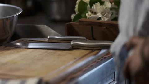 A man is standing in front of a wooden cutting board and knives  Stock Footage 145354902