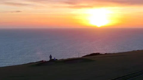 A man is standing on a golf course overlooking the ocean Stock Footage 298253617