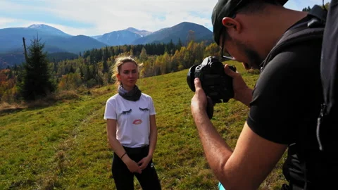 A man that is standing in the grass. Guy with a camera takes pictures of a girl Stock Footage 139871214
