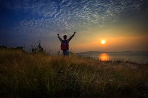 Man standing on grass mountain with sun rising Stock Photos