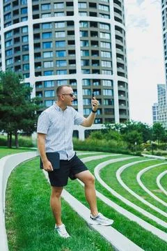 Man standing on grass steps in a modern urban area talking on his phone whi.. Stock Photos