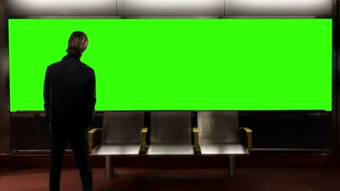 Man Standing Before Green Screen Display in Station Waiting Area Stock Footage 342148586