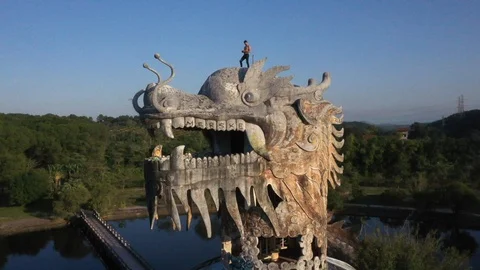 Man Standing on Head of Dragon Statue in Vietnam Abandoned Water Park Aerial Stock Footage 122211042