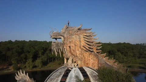 Man Standing on Head of Dragon Statue in Vietnam Abandoned Water Park Rotain Stock Footage 122211211