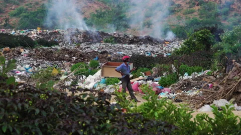 A man standing in heap of garbage and watching it burn. Stack of different Video stock 156880959