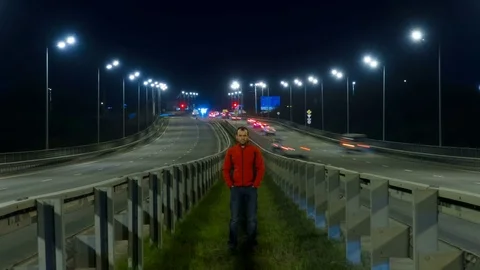 A man is standing on the highway. Freeway traffic blurry cars at night time l Stock Footage 82674119