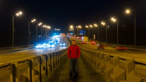 A man is standing on the highway. Freeway traffic blurry cars at night time l Video stock 82934547