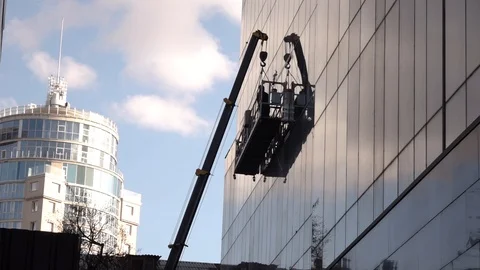 A man standing on a horizontal platform cleaning the windows Stock Footage 118957343