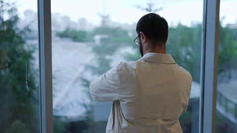 Man standing inside modern interior from rear view at large floor to ceiling Stock Footage 347020628