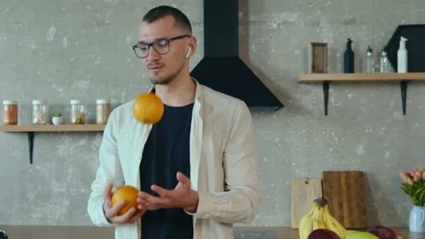 Man standing in the kitchen and attending an online conference while juggling Stock Footage 168998027