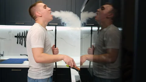 Man Standing in Kitchen. Preparing Dinner. Breakfast. Dinner. Smokes Hookah Stock Footage 147047357