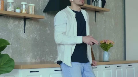 Man standing in the kitchen talking through headphones to co-workers, gesturing Stock Footage 194460363