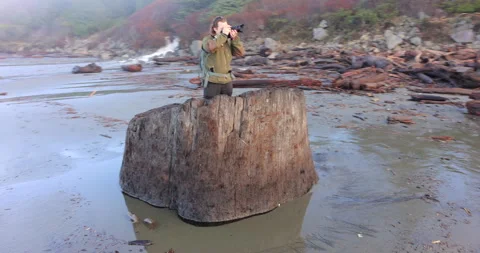 A man is standing on a log in the ocean Stock Footage 270461230