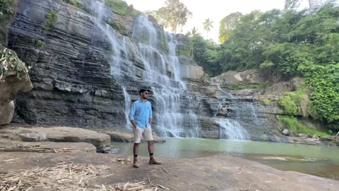 Man Standing, Looking Confident at Multitiered Waterfall, Forest, Wide Shot Stock Footage 324772663