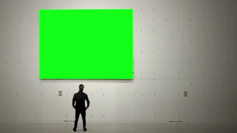 Man Standing in Minimalist Gallery Staring at Large Green Screen Canvas Stock Footage 341670227