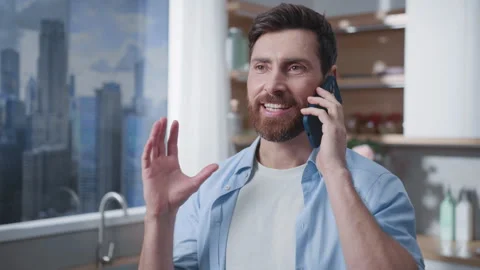 A man is standing in a modern kitchen while making a phone call, engaging in Stock Footage 316037108
