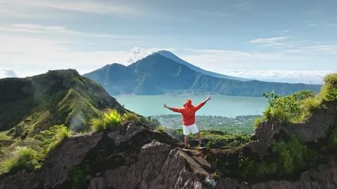Man standing on Mount Batur summit enjoying freedom in Bali Stock Photos