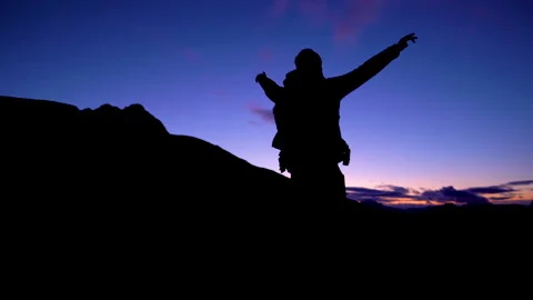 Man standing on mountain after sunset with beautiful sky in the background Stock Footage 143380867