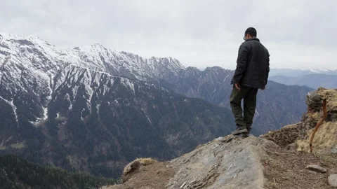 Man Standing on a Mountain Cliff Overlooking Snow Covered Himalayan Peaks Stock Footage 344015346