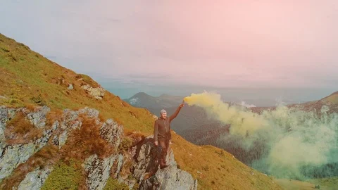 The man standing on the mountain edge with a colored hand smoke Stock-Footage 120003077