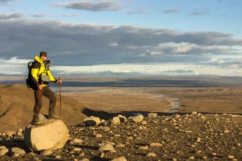 Man standing on mountain rock in dramatic illuminated landscape panorama in Stock Photos