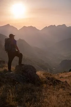 Man standing on a mountain summit looking to the red sunset Stock Photos