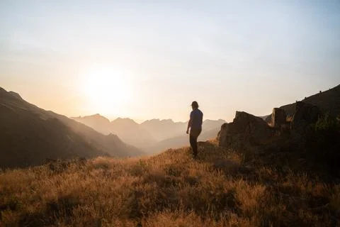 Man standing on a mountain summit looking to the red sunset Stock Photos
