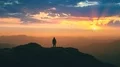 The man standing on the mountain top against a beautiful sunset 4k or 4k+ Resolution
