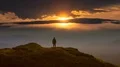The man standing on a mountain top against the bright sunrise. time lapse 4k or 4k+ Resolution