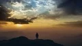 The man standing on a mountain top against a bright sunset. time lapse 4k or 4k+ Resolution