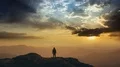 The man standing on a mountain top against the bright sunset. time lapse 4k or 4k+ Resolution