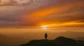 The man standing on a mountain top on the bright sunset background 4k or 4k+ Resolution