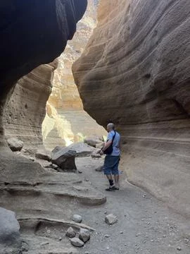 A man is standing in a narrow cave with a backpack on Stock Photos