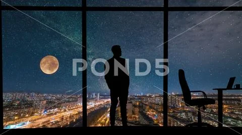 The man standing near the panoramic window on city with starry sky background Stock Photos