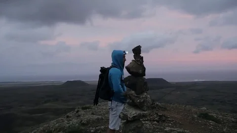 Man standing near stack of rocks on volcanic landscape Stock Footage 71552716