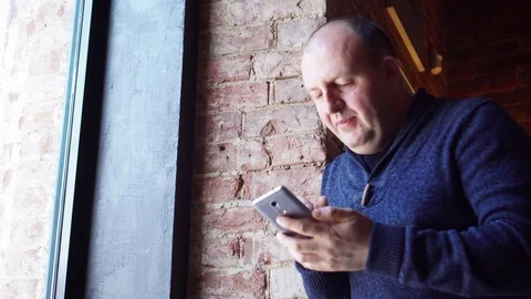 Man standing near a window in a cafe and using smartphone, breakfast Video stock 73127419