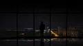 The man standing near the window on the city lightning background 4k or 4k+ Resolution