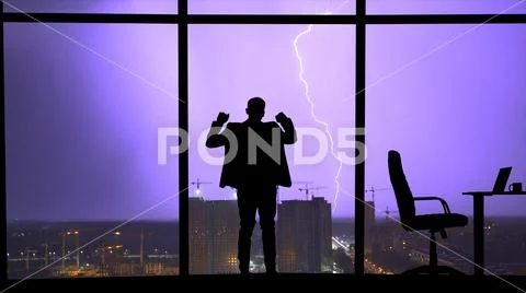 The man standing near the window on a city lightning background Stock Photos