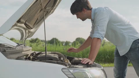 Man standing next to a broke down car, looking down at engine in frustration Stock-Footage 134910288