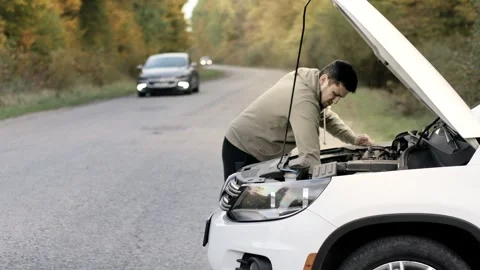 Man standing next to a broke down car and examining in frustration Stock Footage 246944132
