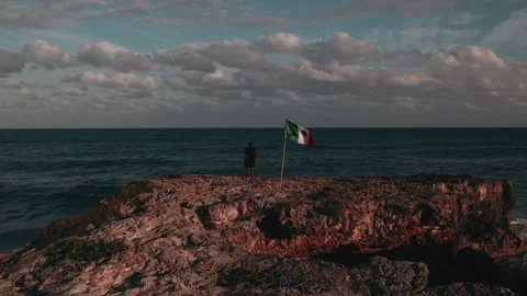 Man standing next to Mexican flag on Scenic background Stock Footage 233437392