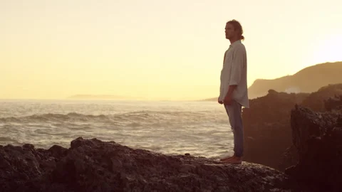 Man standing next to the ocean at sunset and looking out Stock Footage 279790896