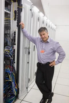 Man standing next to a server tower Stock Photos