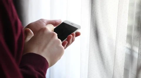 Man standing next to the window and using mobile phone. Close up. Stock Footage 61281250